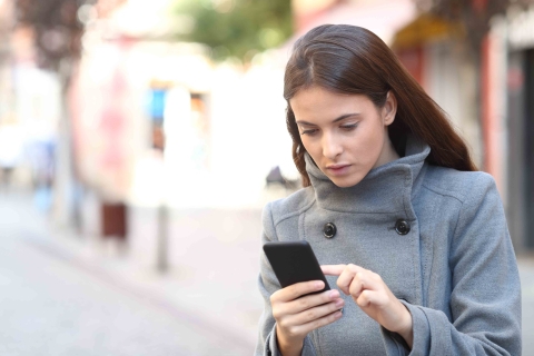 FEMME DANS LA RUE SUR SON TELEPHONE SMARTPHONE