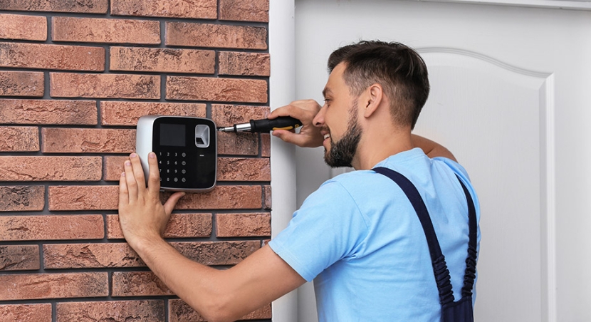 Un installateur est en train de poser une alarme